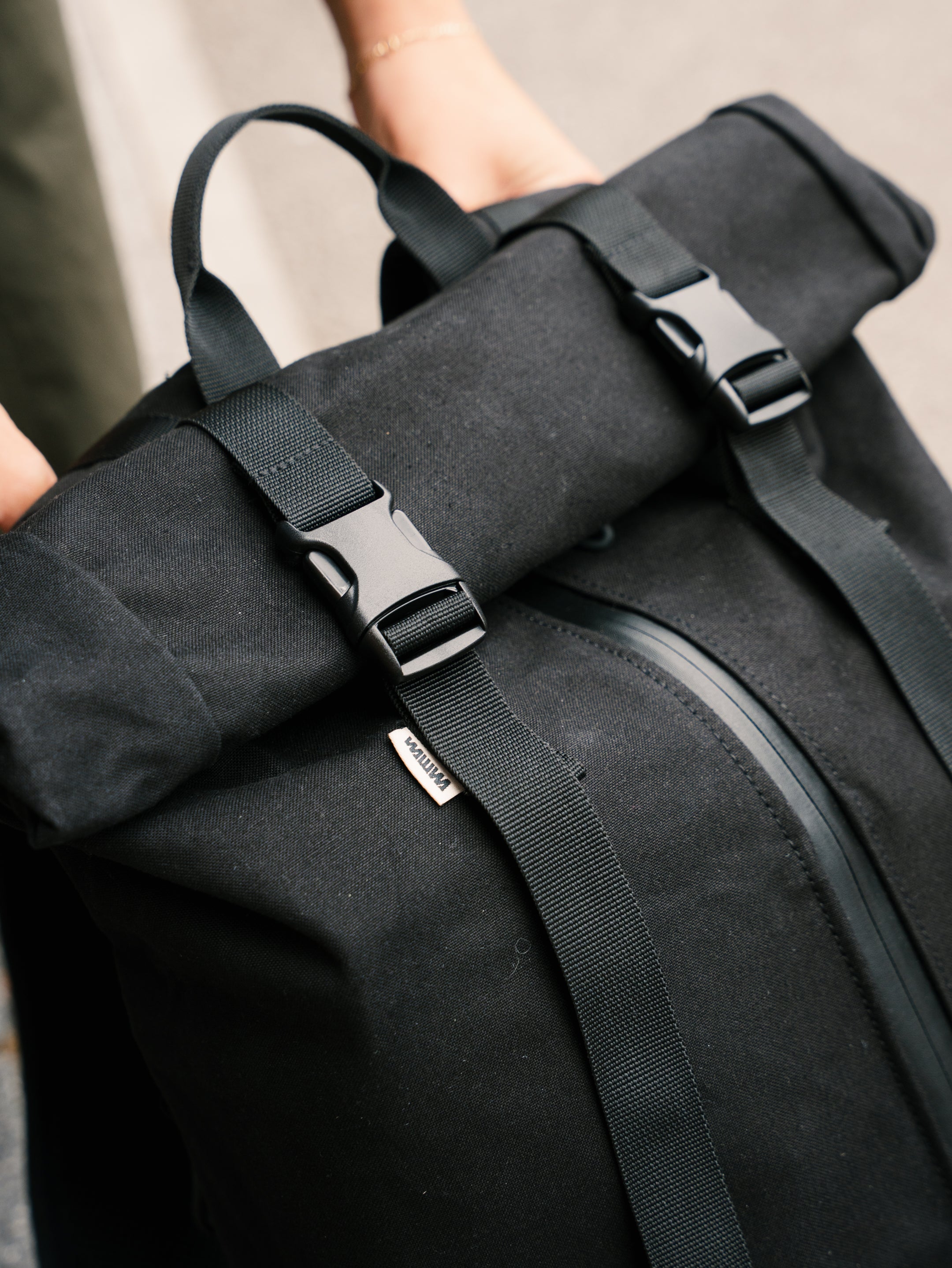 Roll-top buckle closure detail on the Bridge Backpack in Black