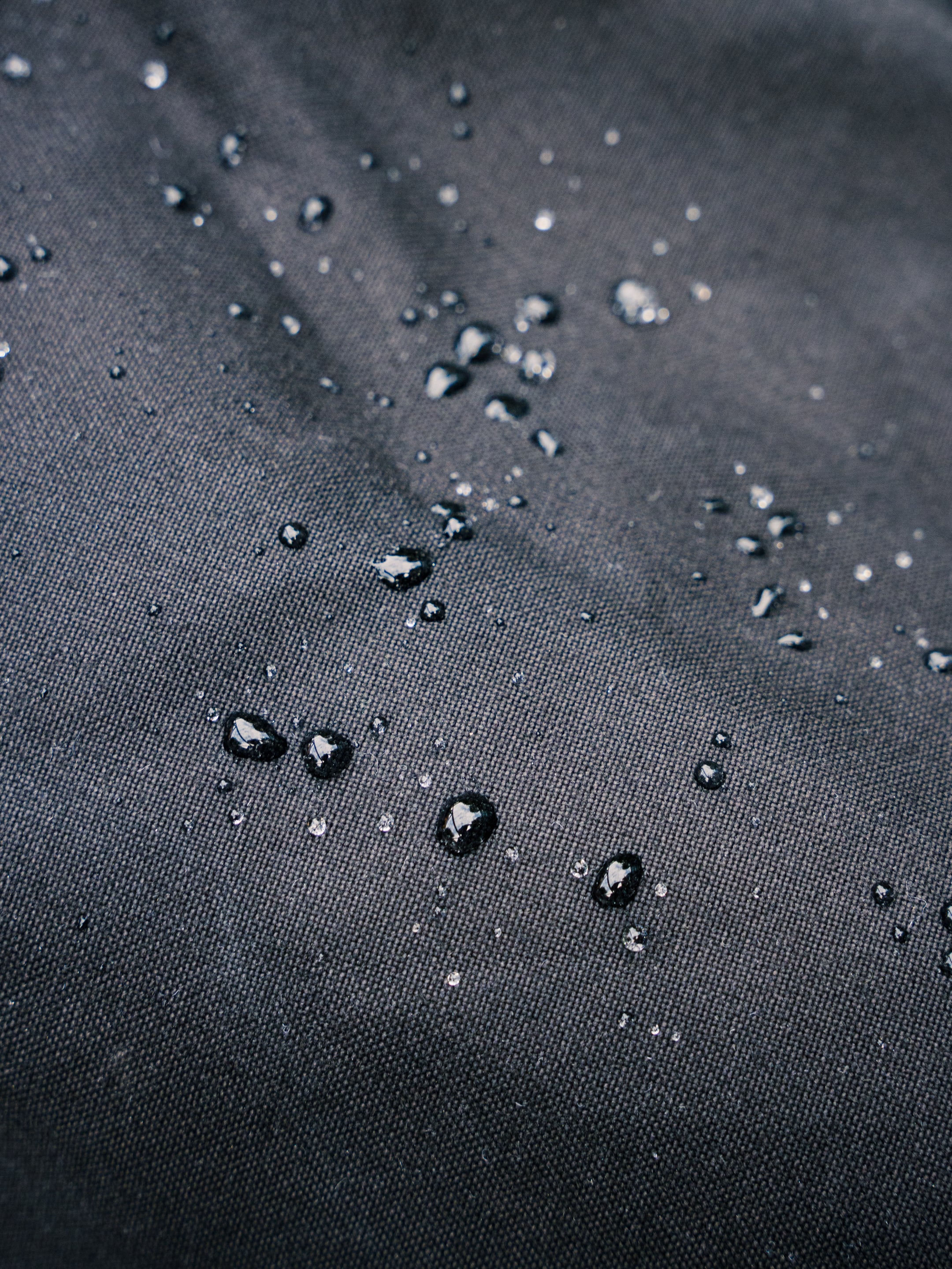 Water beading on the water-resistant fabric of the Bridge Backpack in Black