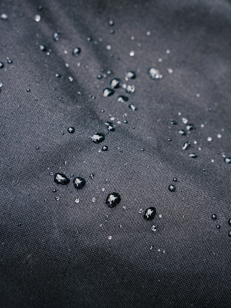 Water beading on the water-resistant fabric of the Bridge Backpack in Black